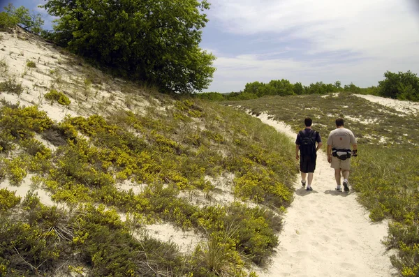 Two tourists walking in dunes — Stock Photo, Image