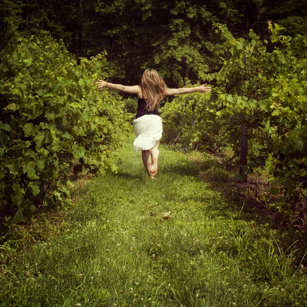 Woman running through a vineyard — Stock Photo, Image