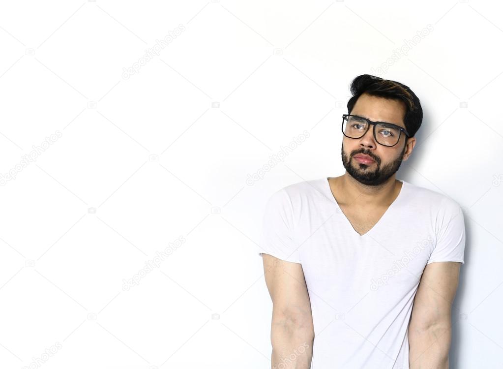 Portrait of thoughtful young handsome Indian man wearing glasses