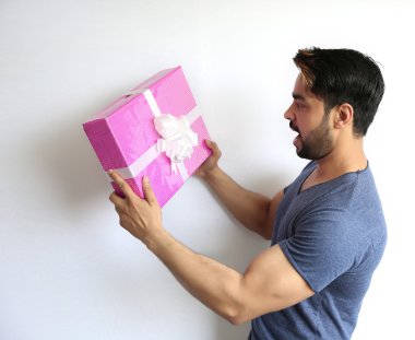 Beyaz arka planda izole edilmiş hediye kutusunu tutan hintli genç bir adam.