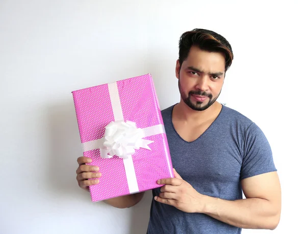 Beyaz arka planda izole edilmiş hediye kutusunu tutan hintli genç bir adam.