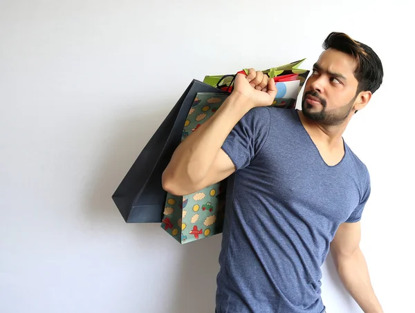 A young Indian man holding shopping bags on white background. — Stock Photo, Image