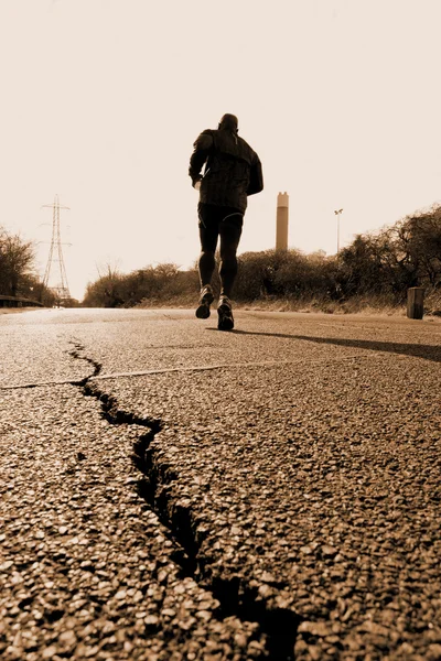 Бегущий по потрескавшейся дороге — стоковое фото