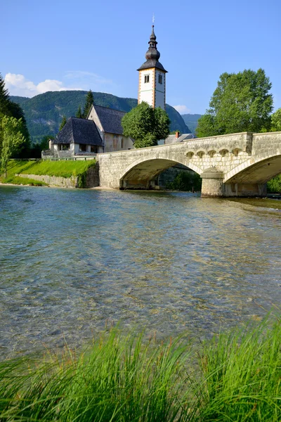 Igreja de São João Velho e ponte de pedra no lago Bohinj, Eslovênia — Fotografia de Stock