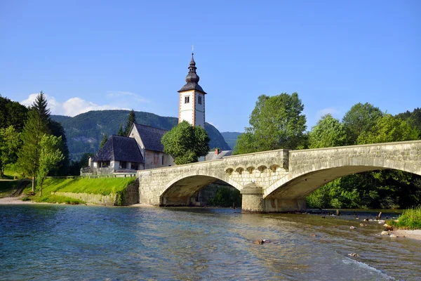 Antigua iglesia de San Juan y puente de piedra en el lago Bohinj, Eslovenia —  Fotos de Stock