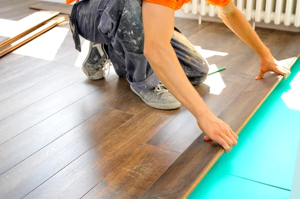 Carpintero haciendo trabajo de piso laminado — Foto de Stock