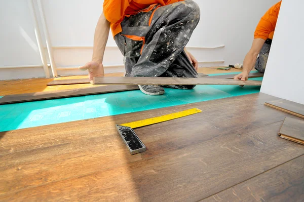 Carpintero haciendo trabajo de piso laminado — Foto de Stock