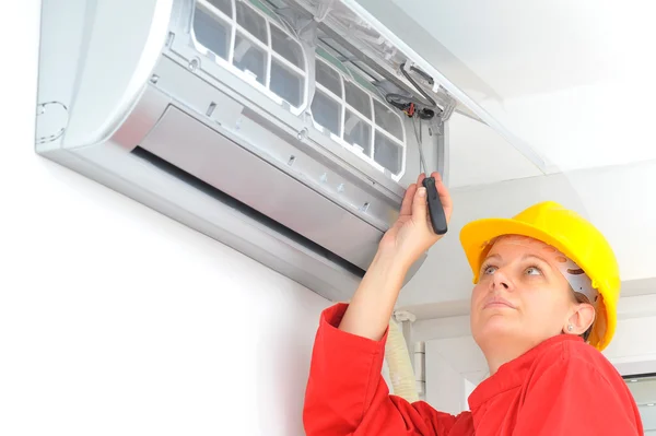 Женщина-работница регулирует систему кондиционирования воздуха — стоковое фото