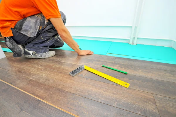 Carpintero haciendo trabajo de piso laminado — Foto de Stock
