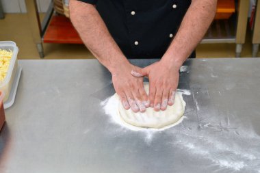 Pizza yapma süreci, aşçı aşçının mutfakta pizza yapmasıyla sonuçlanır..