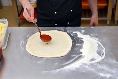 Pizza yapma süreci, aşçı aşçının mutfakta pizza yapmasıyla sonuçlanır..