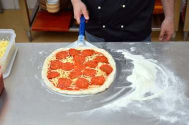 Pizza yapma süreci, aşçı aşçının mutfakta pizza yapmasıyla sonuçlanır..