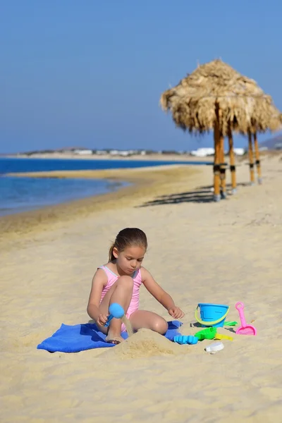 Adorable niña jugando con sus juguetes en la playa —  Fotos de Stock