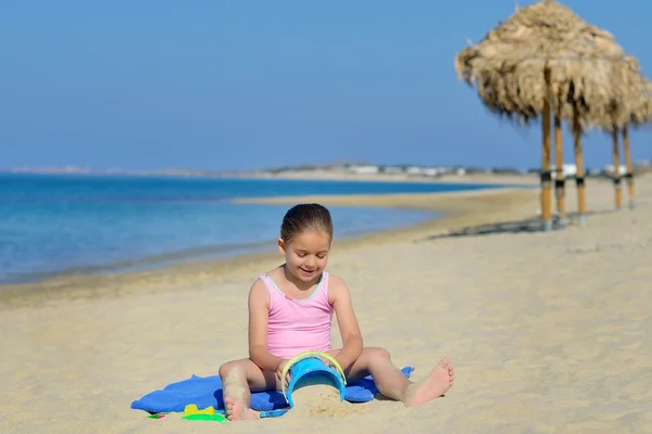 Очаровательная девочка, играющая со своими игрушками на пляже — стоковое фото