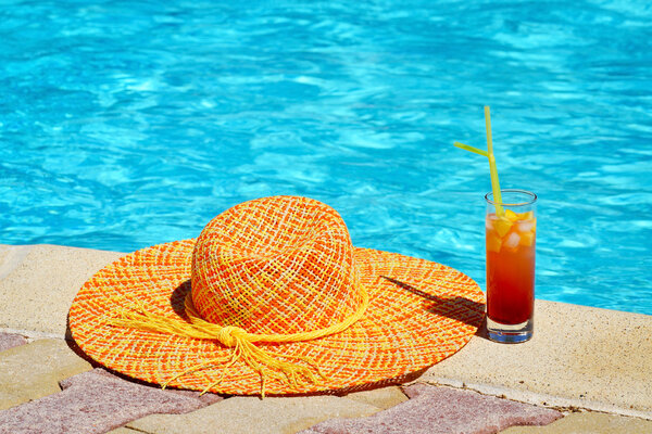 Женская шляпа с коктейлем у бассейна
