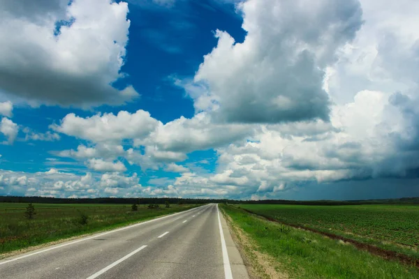 Landscape overlooking the road through fields and sky with clouds