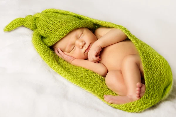 Новорожденный ребенок спит, спящий новорожденный малыш обмотан зеленой тканью — стоковое фото