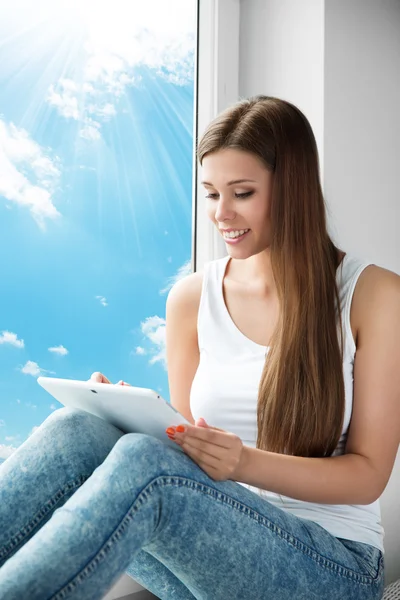 Vrouw met behulp van de Tablet op venster, jong meisje lezing witte touchpad — Stockfoto