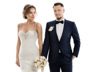 Düğün Çift Moda Portresi. Klasik Takım Elbiseli Gelinlik ve Damat ile Çiçekli Gelin İzole Beyaz Stüdyo Arkaplanı