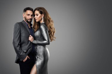 Moda Çifti Manken Kadın. Gümüş Elbiseli Lüks Cazibeli Kız ve Takım Elbiseli Adam. Gece Saç Tarzı ve Gri Arkaplanda Makyaj