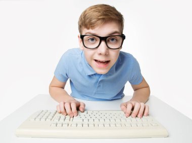 Bilgisayar Klavyesini kullanan Şaşkın Çocuk. Genç Hacker dizüstü bilgisayarda daktilo kullanıyor. Gözlüklü Komik Çocuk Beyaz Stüdyo Arkaplanı Üzerinde Program Çalışması Kodu