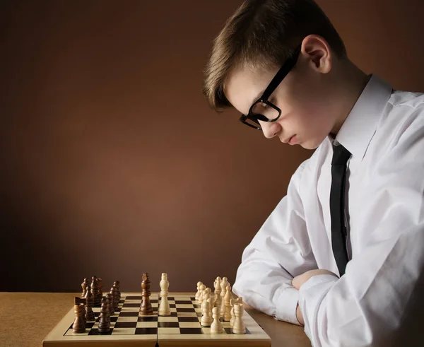 Concentrated serious boy developing chess gambit, strategy ,playing board  game to winner clever concentration and thinking child while playing chess.  Learning, tactics and analysis concept. Free Photo