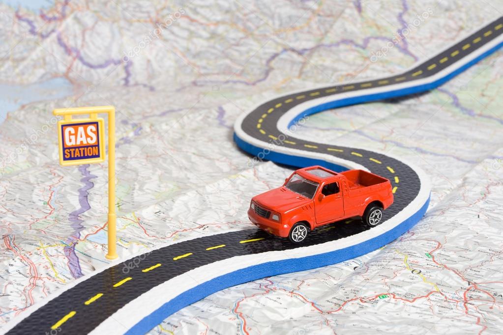 Toy car on roadmap showing petrol station, travel concept