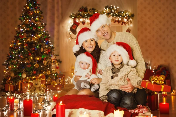 Retrato de família de Natal em casa férias sala de estar, crianças e bebê no chapéu de Santa com caixa de presente presente, casa de decoração por velas de árvore de Natal guirlanda — Fotografia de Stock