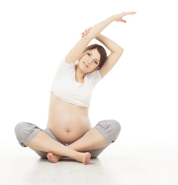 妊娠中の女性ヨガを行使します。妊娠妊婦の健康管理と運動体操。足の白い背景を渡った母蓮華座に座っています。 — ストック写真