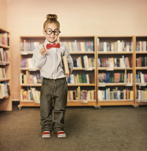 Ragazzo della scuola in biblioteca, Bambino in occhiali con libro, Libreria studentesca ragazza scaffali — Foto Stock