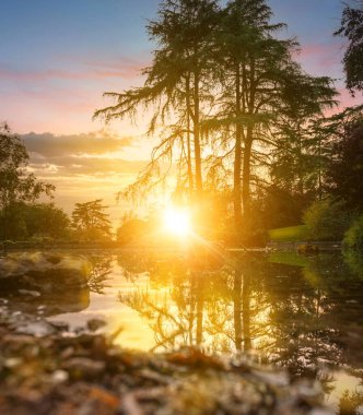 Güneşin son ışınları parktaki gölete yansıyor.