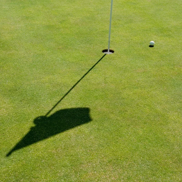 Buraco de golfe, bandeira e bola — Fotografia de Stock