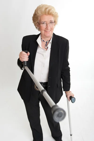 Smiling senior woman with crutches — Stock Photo, Image