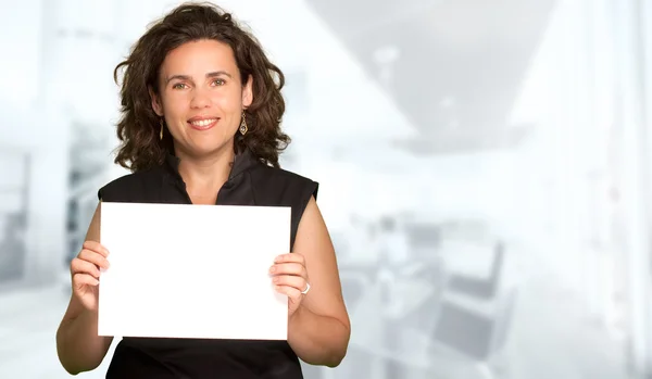 Vrouw presenteren een leeg teken in office achtergrond — Stockfoto