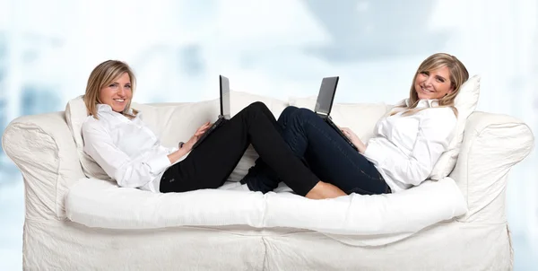 Meninas no sofá com simetria laptop — Fotografia de Stock