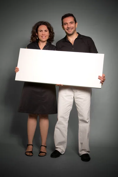 Cheerful couple holding a blank sign — Stock Photo, Image