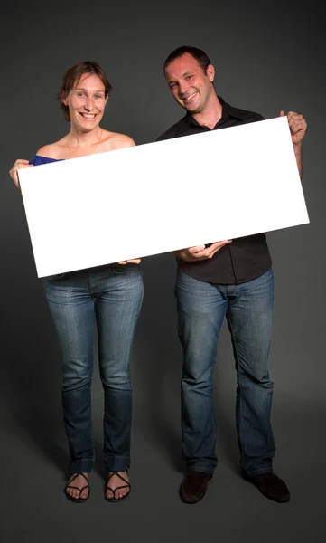 Casal segurando um sinal em branco — Fotografia de Stock