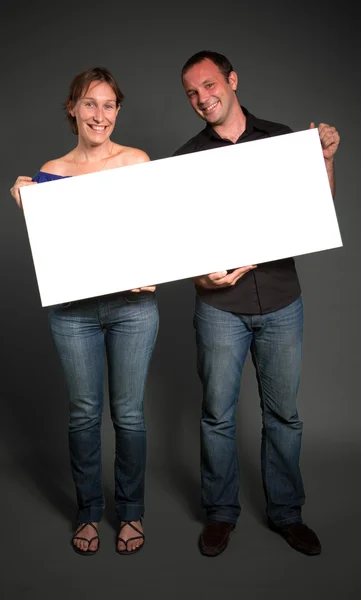 Pareja sosteniendo un cartel en blanco — Foto de Stock