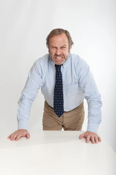 Homem de negócios irritado apoiando-se em uma mesa — Fotografia de Stock