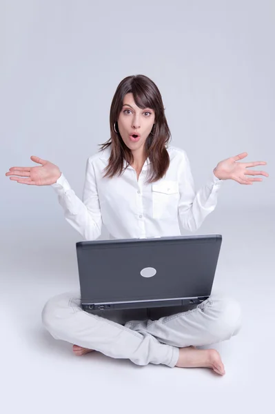 Verrast jonge vrouw met laptop op de verdieping — Stockfoto