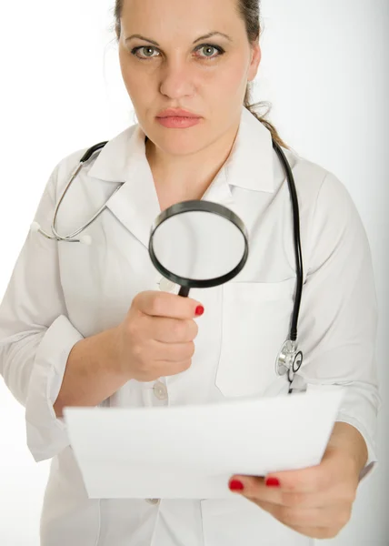 Médico femenino serio analizando documento —  Fotos de Stock