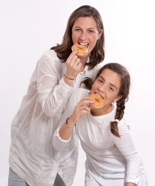 Happy mother and daughter eating donuts — Stock Photo, Image