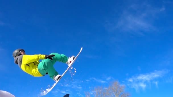 Deportista volador en el fondo del cielo. Snowboarder hace la rotación en el aire — Vídeos de Stock