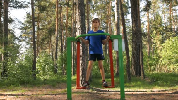 Young Boy doing fitness on gymnastic equipment outdoors — Stock Video