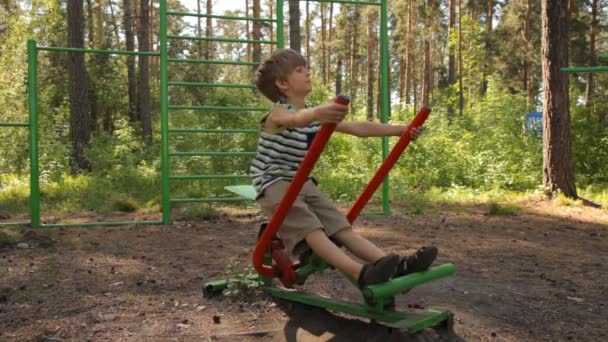 Little boy training on playground equipment — Stock Video