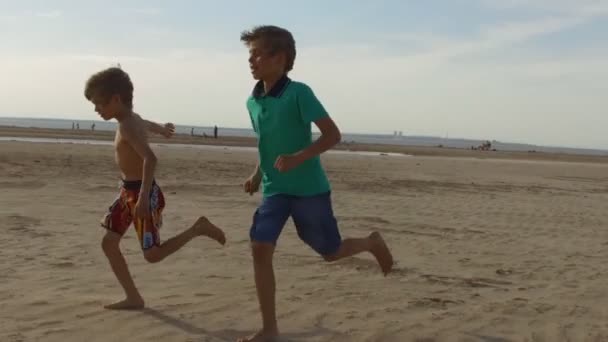 Niños jugando al fútbol en una playa — Vídeo de stock