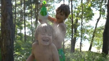  Çocuk küçük kardeşi püskürtücü üzerinden sıcak yaz gün sulama. 