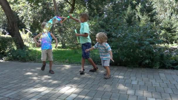 Tres niños se divierten con grandes burbujas de jabón — Vídeos de Stock