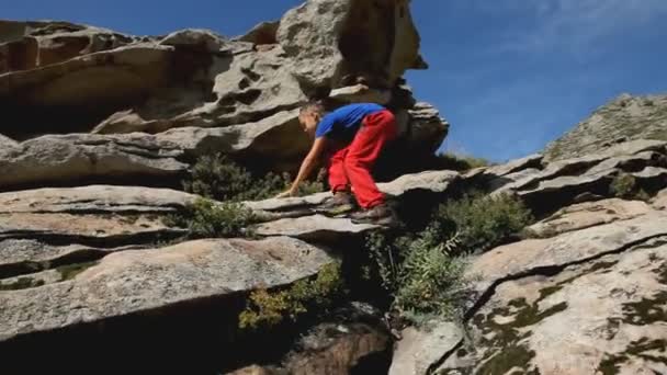 Aktiv pojke klättring på toppen av berget — Stockvideo