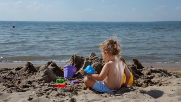 Lindo bebé jugando con arena en la playa — Vídeo de stock